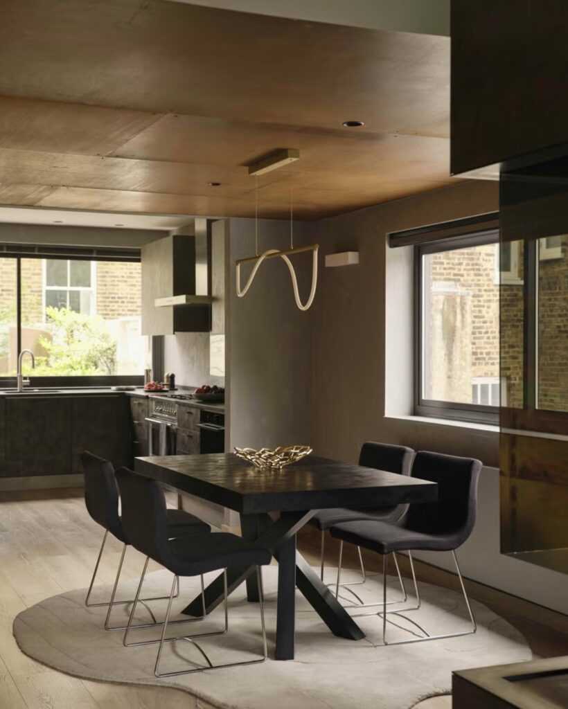 A Modern London House Dining Area With A Dark Wood Table, Sleek Black Chairs, And A Unique Pendant Light. The Room Features A Minimalist Design And A Neutral Color Palette.