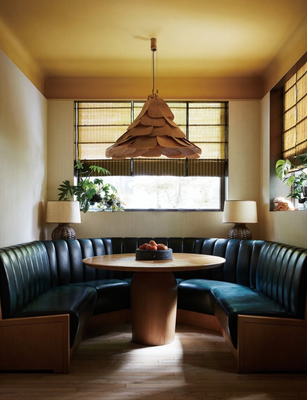 Breakfast Nook: The Curved Banquette Seating, Upholstered In Deep Green Leather With Vertical Tufting, Embraces A Round Wooden Table At Its Center.