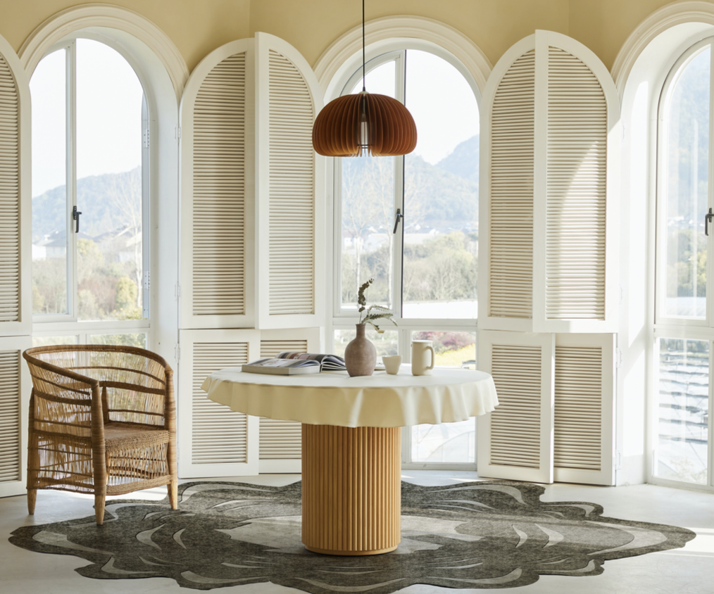 Elegant Dining Room With A Round Table On A Designer Rug, Set Against Arched Windows And Natural Light.