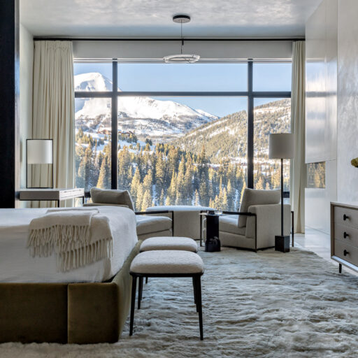 This Luxurious Bedroom Offers A Stunning View Of Mountain Houses Nestled Amidst The Peaks. The Room Features A Plush Bed, Stylish Furniture, And A Large Window Overlooking The Breathtaking Landscape.