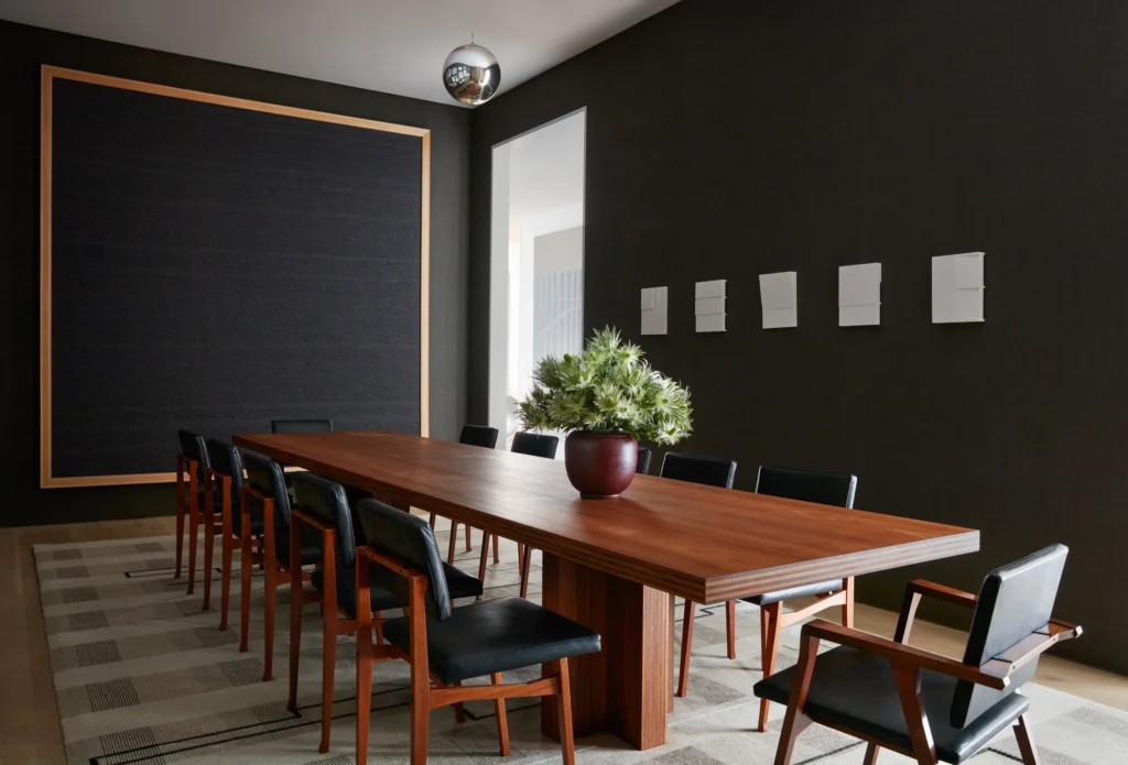 A Dining Room With Wooden Tones Furniture And Black Walls.