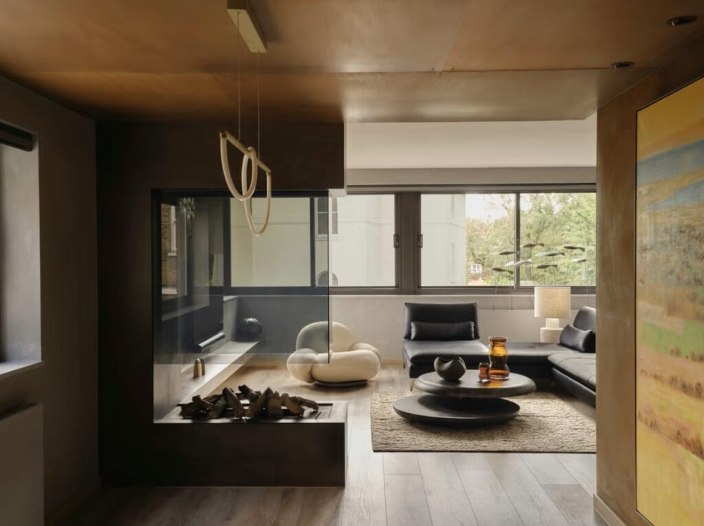 A Stylish London House Living Room With A Modern Fireplace, Plush Seating, And Unique Pendant Lights. The Design Blends Contemporary And Cozy Elements.