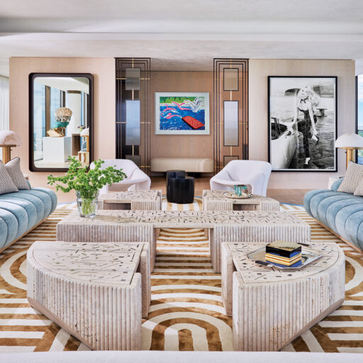 A Modern Miami Living Room Boasts Plush Blue Sofas, Geometric Tables, And Bold Art. Sunlight Streams In, Highlighting The Chic, Curated Space.